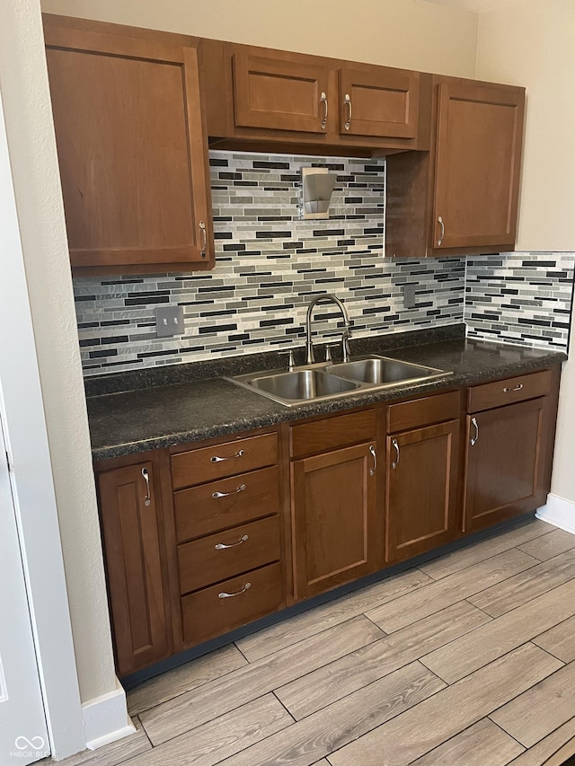 kitchen featuring dark countertops, light wood-style floors, and a sink