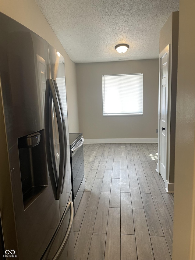 kitchen featuring a textured ceiling, wood finish floors, range with electric cooktop, baseboards, and stainless steel fridge with ice dispenser