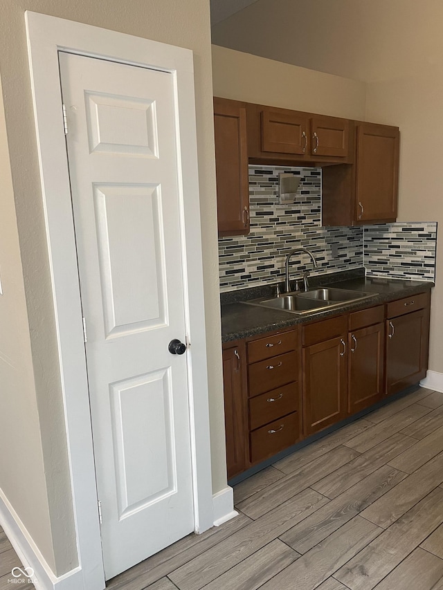 kitchen with light wood finished floors, dark countertops, and a sink