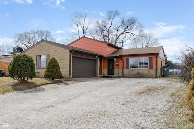 view of front of house featuring gravel driveway, brick siding, and an attached garage