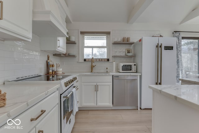 kitchen featuring light stone counters, white appliances, a sink, white cabinetry, and open shelves