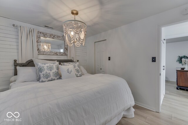 bedroom featuring visible vents, baseboards, light wood-style flooring, and an inviting chandelier