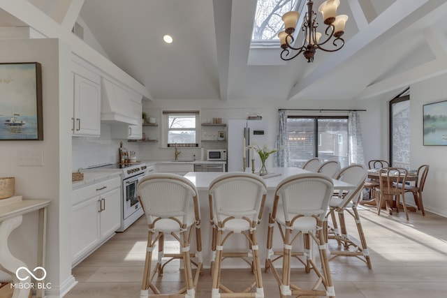 kitchen featuring pendant lighting, open shelves, light countertops, white cabinetry, and white appliances