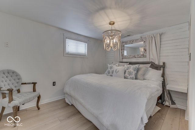 bedroom with a notable chandelier, light wood-style flooring, and baseboards