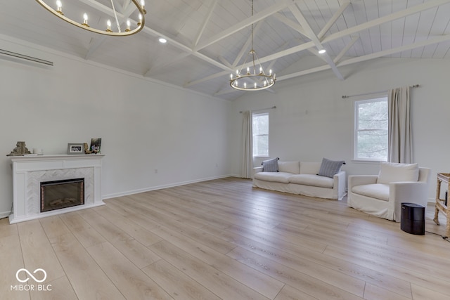 unfurnished living room with vaulted ceiling with beams, light wood-style flooring, a high end fireplace, and a notable chandelier