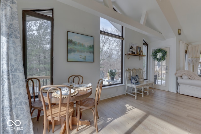 dining room featuring light wood finished floors and vaulted ceiling