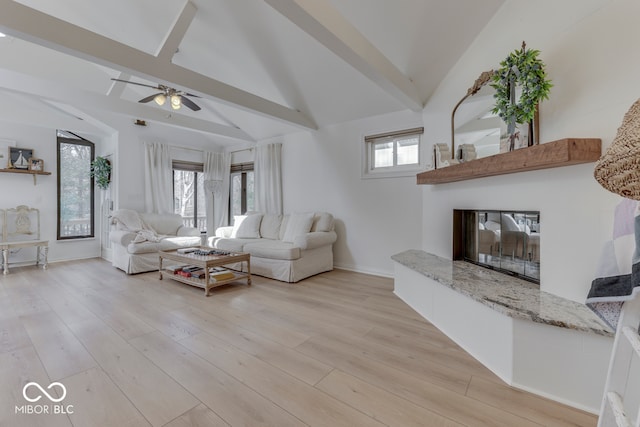 living area featuring a healthy amount of sunlight, lofted ceiling with beams, and light wood finished floors