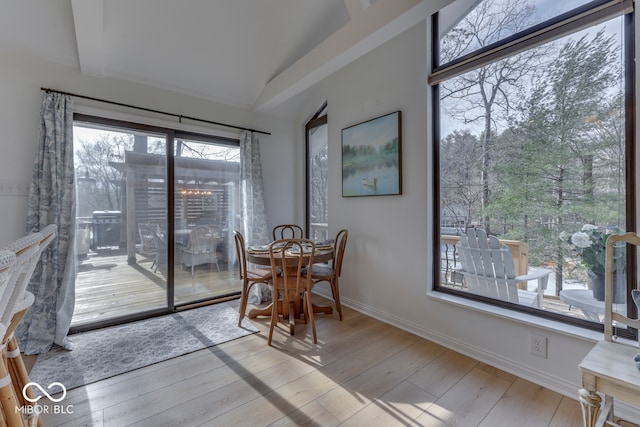 dining area with light wood-style floors, lofted ceiling, and baseboards