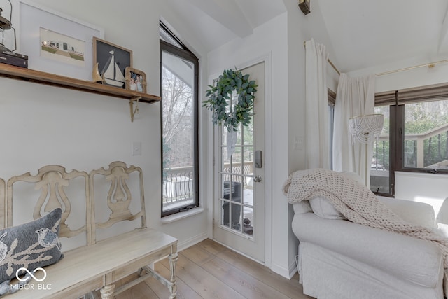 living area featuring light wood-style floors, lofted ceiling, and baseboards