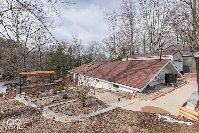 exterior space featuring roof with shingles and cooling unit