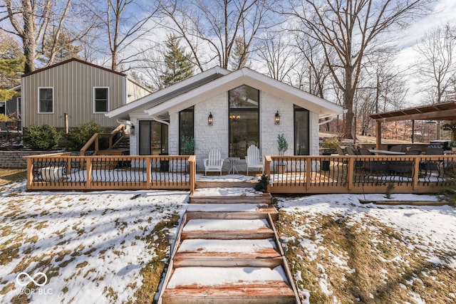 view of front of house featuring stone siding, a deck, and board and batten siding