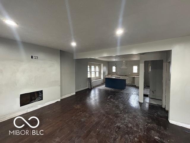 unfurnished living room with dark wood-type flooring, a fireplace, and baseboards