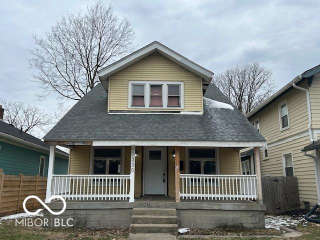 bungalow-style house with a shingled roof, fence, and a porch