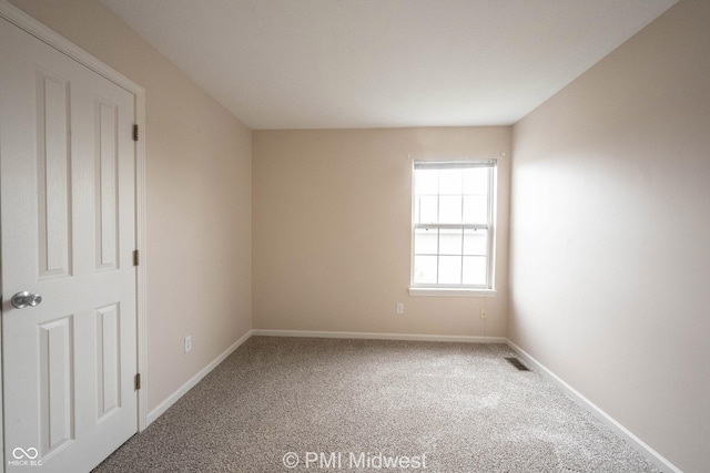 carpeted spare room with visible vents and baseboards