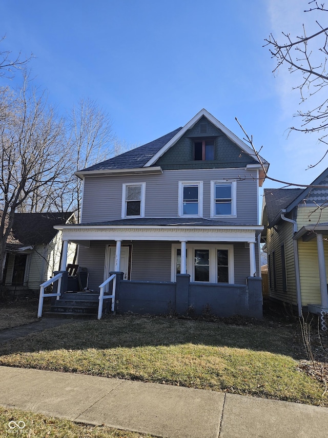 view of front of property featuring a porch, roof with shingles, and a front yard