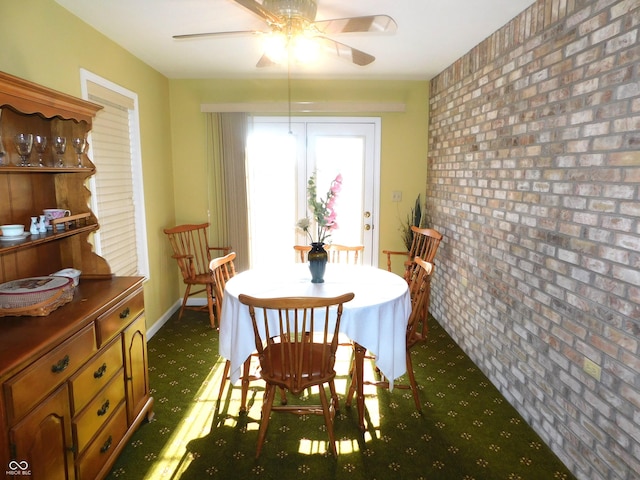 dining area featuring brick wall, a ceiling fan, and baseboards