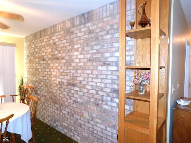 dining room with a ceiling fan and brick wall