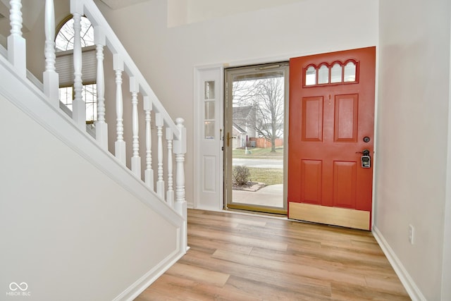 entryway featuring light wood-type flooring, baseboards, and stairs