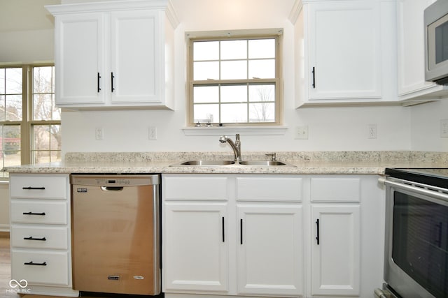 kitchen featuring stainless steel appliances, a wealth of natural light, a sink, and white cabinetry