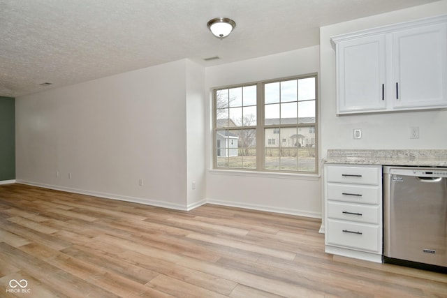 kitchen with a textured ceiling, white cabinets, baseboards, light wood-type flooring, and dishwasher