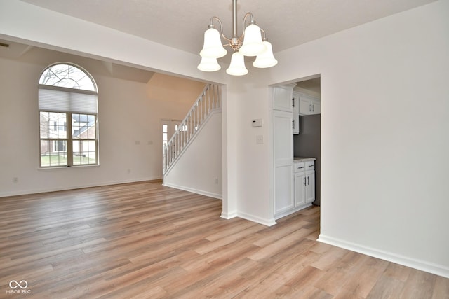 interior space with a notable chandelier, visible vents, baseboards, stairs, and light wood-type flooring