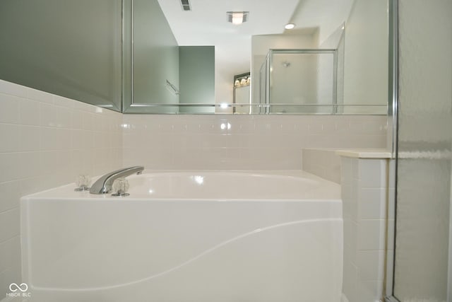 bathroom featuring a stall shower, visible vents, tile walls, and a bath