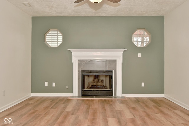 unfurnished living room featuring a textured ceiling, a fireplace, a ceiling fan, and wood finished floors