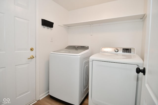 laundry area with laundry area, washer and clothes dryer, and wood finished floors