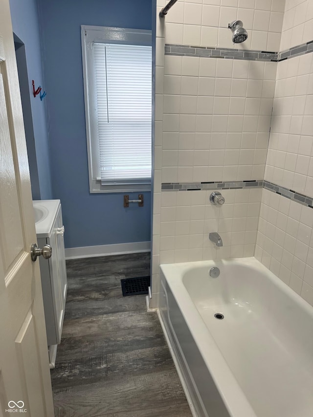 full bathroom featuring wood finished floors, visible vents, vanity, baseboards, and shower / washtub combination