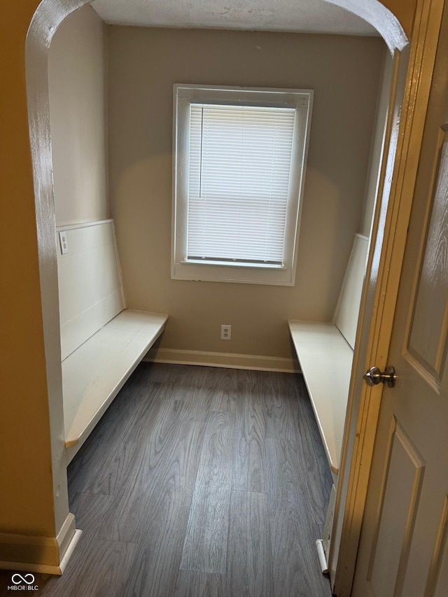 mudroom featuring arched walkways, dark wood-style floors, and baseboards