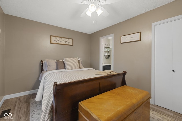 bedroom featuring light wood finished floors, ensuite bath, baseboards, and ceiling fan