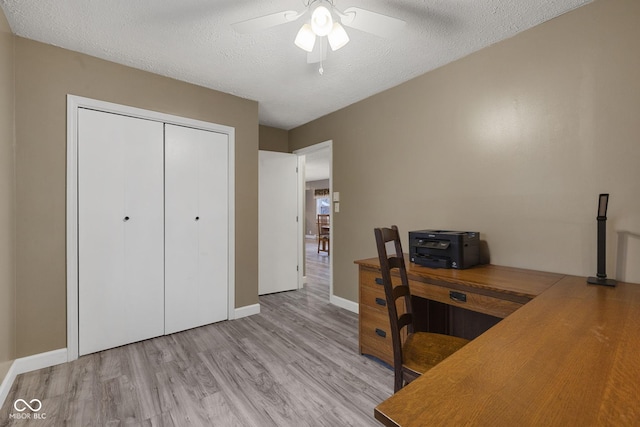 unfurnished office featuring light wood finished floors, baseboards, a ceiling fan, and a textured ceiling