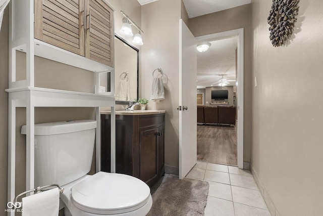 bathroom with toilet, a ceiling fan, vanity, baseboards, and tile patterned floors