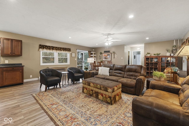 living area featuring baseboards, a ceiling fan, a textured ceiling, light wood-type flooring, and recessed lighting