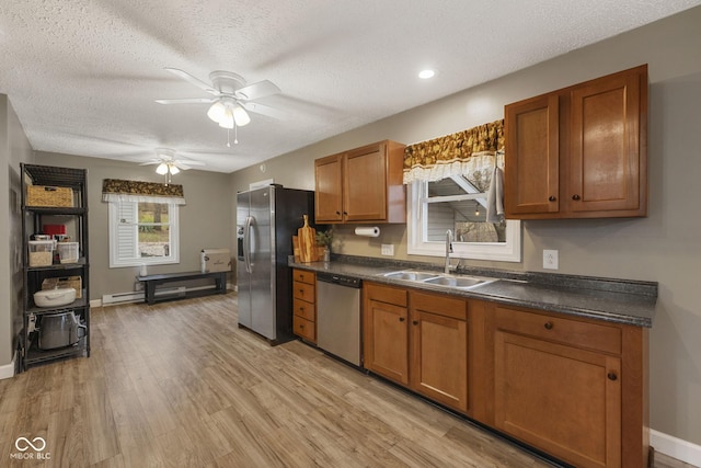 kitchen featuring stainless steel appliances, brown cabinetry, dark countertops, and a sink