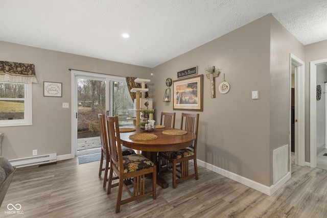 dining room with visible vents, light wood finished floors, and baseboard heating