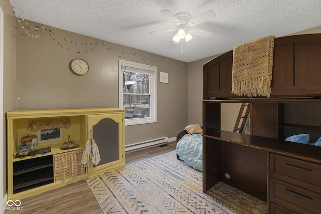 home office featuring light wood-style floors, a ceiling fan, a baseboard heating unit, and a textured ceiling