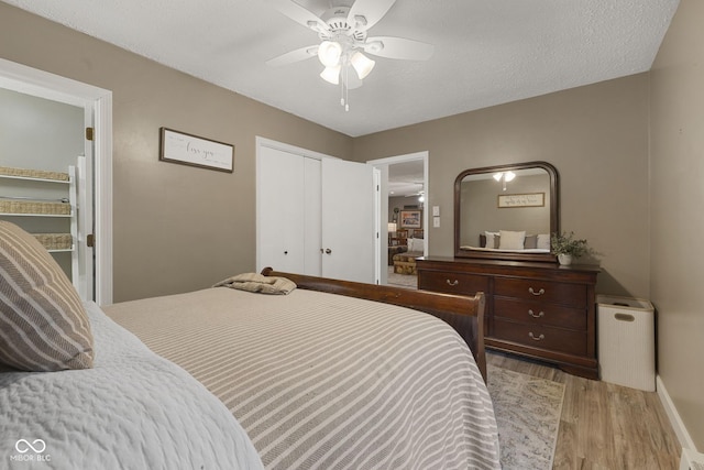 bedroom with a textured ceiling, a closet, light wood-type flooring, and a ceiling fan