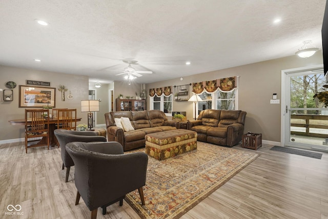 living area with light wood finished floors, baseboards, a textured ceiling, and recessed lighting