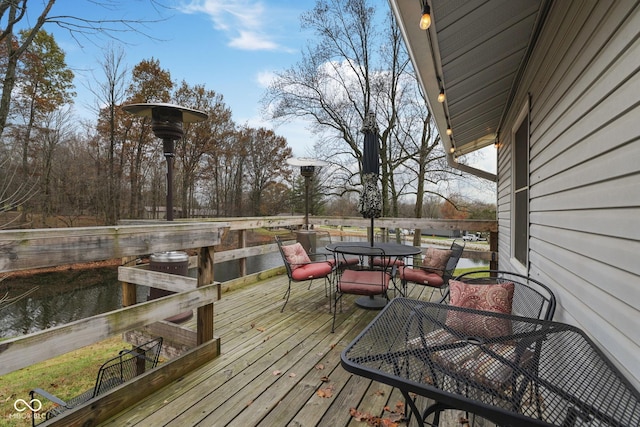 wooden terrace with outdoor dining area and a water view