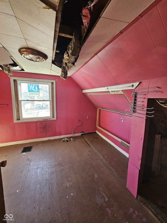 additional living space with dark wood finished floors, visible vents, vaulted ceiling, and baseboards