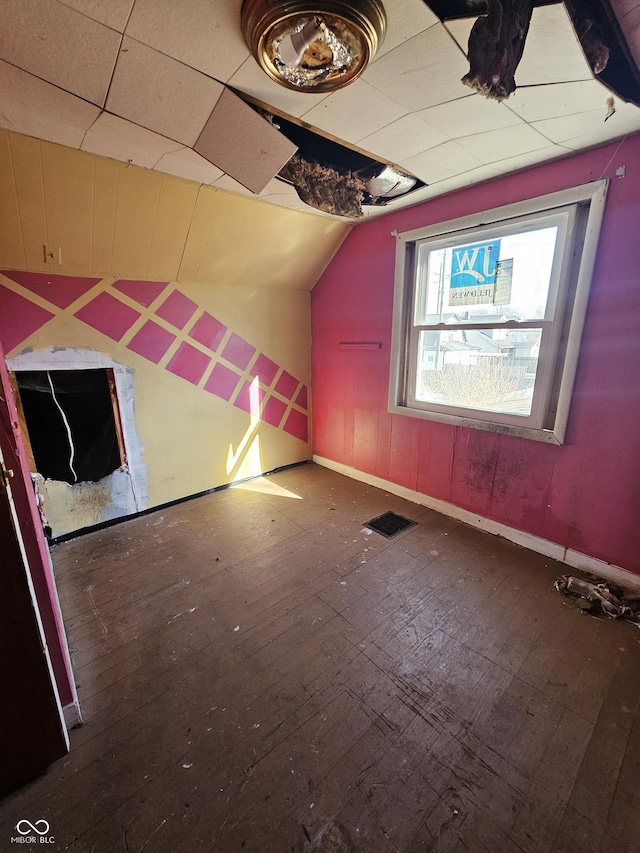 bonus room featuring lofted ceiling, visible vents, baseboards, and wood finished floors