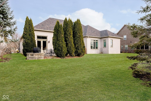 rear view of house with french doors, brick siding, and a lawn