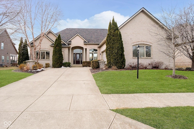 french country home with concrete driveway, brick siding, and a front lawn