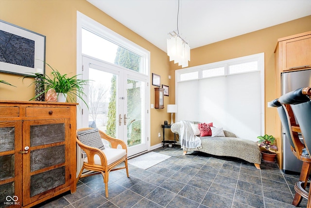 sitting room with stone finish flooring, baseboards, and french doors