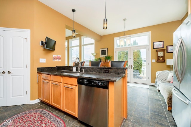 kitchen featuring a peninsula, appliances with stainless steel finishes, a sink, and a healthy amount of sunlight