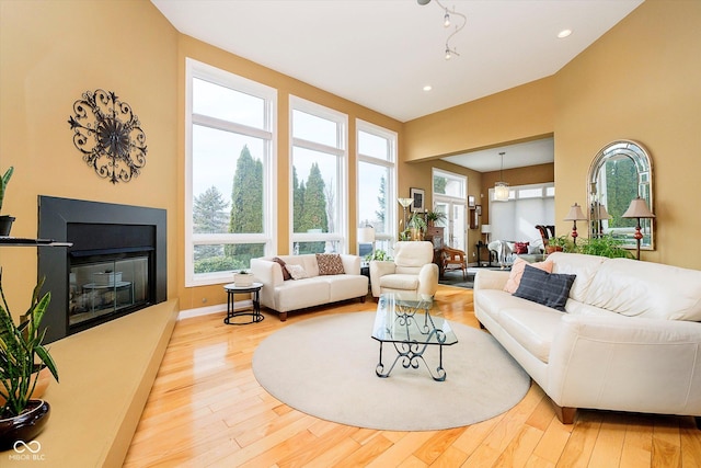 living room featuring recessed lighting, baseboards, wood finished floors, and a glass covered fireplace