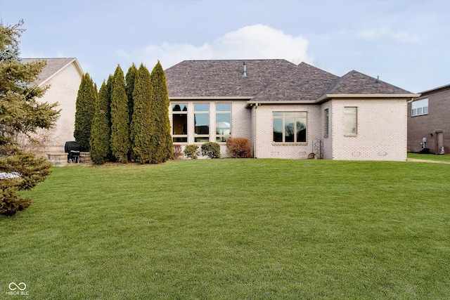 rear view of property featuring crawl space, brick siding, a lawn, and a shingled roof