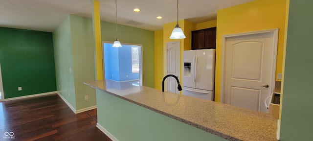 kitchen featuring baseboards, dark wood-style floors, white fridge with ice dispenser, pendant lighting, and a sink