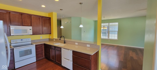 kitchen featuring a peninsula, white appliances, pendant lighting, and a sink